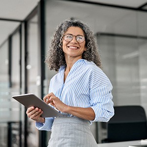 Woman smiling while holding tablet in office
