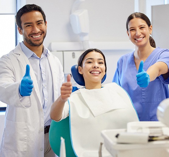 Dentist, patient, and hygienist all giving a thumbs up