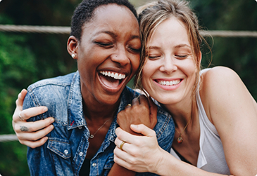 Smiling woman side hugging a laughing woman